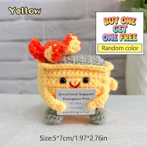 May include: A yellow crocheted dumpster fire with a smiling face, orange flames, and gray wheels. It has a sign that reads "Emotional Support Dumpster Fire." The size is 1.97" x 2.76".