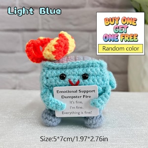 May include: A light blue crocheted dumpster fire with a red and yellow crocheted flame. The dumpster has a smiling face and holds a sign that reads "Emotional Support Dumpster Fire." The size is 1.97*2.76 inches.