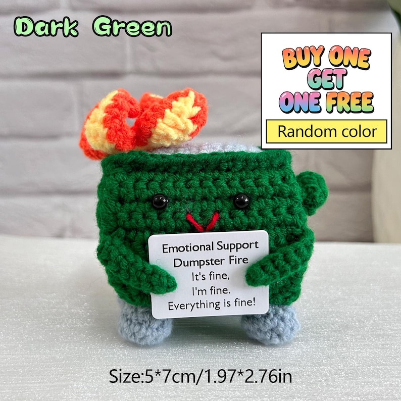 May include: A dark green crochet dumpster with a red and yellow bow, holding a sign that reads "Emotional Support Dumpster Fire." The text "BUY ONE GET ONE FREE" is also visible. The size is 1.97*2.76 inches.