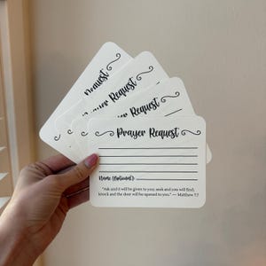 May include: A stack of white prayer request cards with black text. Each card has the words "Prayer Request" and lines for writing. A Bible verse is printed at the bottom of the card.