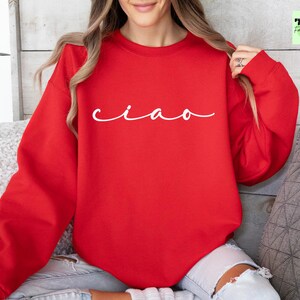K&ouml;nnte beinhalten: Roter Pullover mit dem Wort "ciao" in wei&szlig;er Kursivschrift.