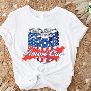 May include: White t-shirt with a graphic of three red, white, and blue American flag-themed beer cans. The text "Ameri'Can" is printed in red above the cans.