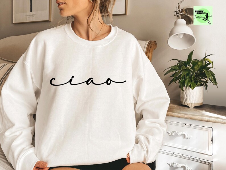 K&ouml;nnte beinhalten: Wei&szlig;er Pullover mit dem Wort "ciao" in schwarzer Kursivschrift.
