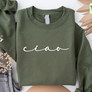 K&ouml;nnte beinhalten: Ein gr&uuml;ner Pullover mit dem Wort "ciao" in wei&szlig; auf der Vorderseite.