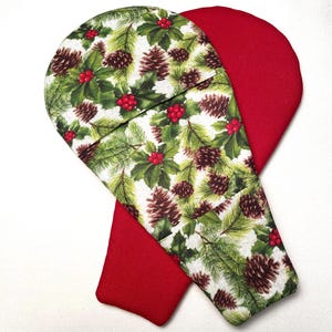 May include: A pair of fabric oven mitts featuring a festive pattern of green pine needles, brown pinecones, and bright red holly berries on a white background, with the reverse side of the mitts in a solid, vibrant red fabric.