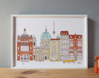 May include: A white framed print of a colorful illustration of a cityscape. The buildings are drawn in a cartoon style and include a church with a green dome, a tower with a red roof, and a yellow tram. The text "Berlin" is printed at the bottom of the print.