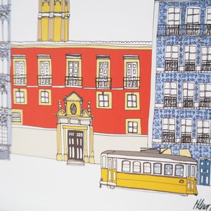 May include: A yellow tram with windows and a door is parked in front of a red building with a blue building to the right. The red building has a large arched doorway and several windows. The blue building has a tiled facade with many windows.