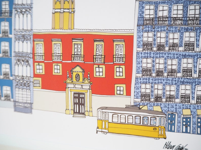 May include: A yellow tram with windows and a door is parked in front of a red building with a blue building to the right. The red building has a large arched doorway and several windows. The blue building has a tiled facade with many windows.