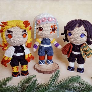 May include: Three handmade crochet dolls, each with unique features. One has yellow and red hair, another has white hair with pink floral accents, and the third has dark purple hair. All dolls wear detailed outfits.