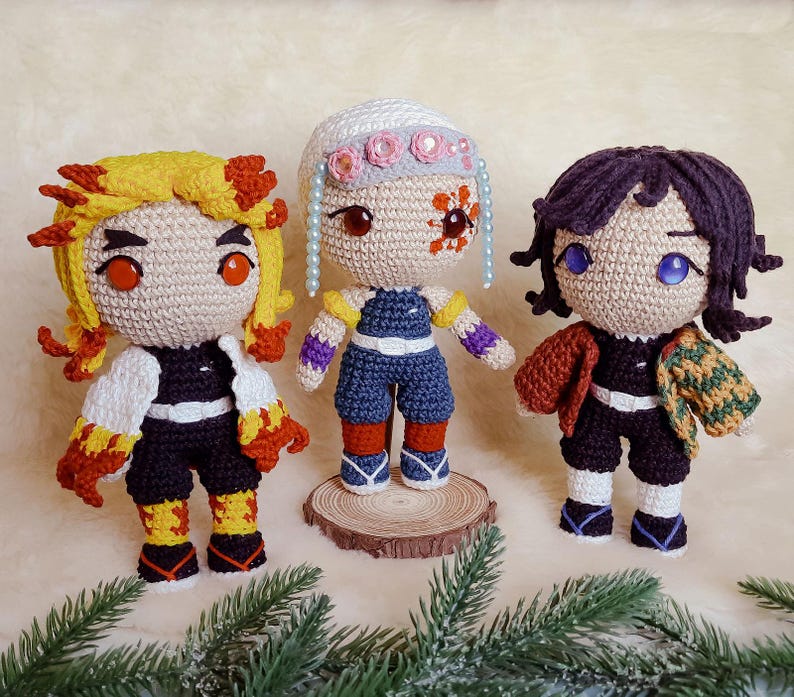 May include: Three handmade crochet dolls, each with unique features. One has yellow and red hair, another has white hair with pink floral accents, and the third has dark purple hair. All dolls wear detailed outfits.