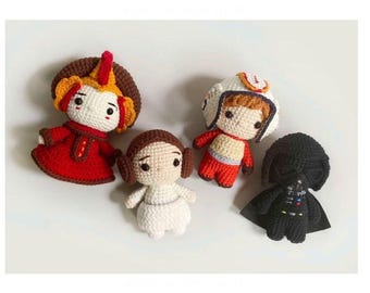 May include: Four crocheted plush toys, including a red and brown character with a crown, a white character with brown hair, a red and white character with a helmet, and a black character with a cape.