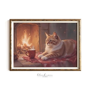 Könnte beinhalten: Gerahmter Druck zeigt eine rot getigerte Katze, die sich auf einer roten Decke in der Nähe eines Kamins ausruht. Eine rote Tasse mit heißem Getränk steht auf einem Tisch. Das Kunstwerk hat eine warme, einladende Ausstrahlung.