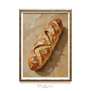 May include: A framed painting of a baguette. The bread is depicted with textured brushstrokes in shades of brown and tan, suggesting a crusty exterior. The background is a muted beige, and the frame is a warm gold color. The painting is signed "black cove studio".