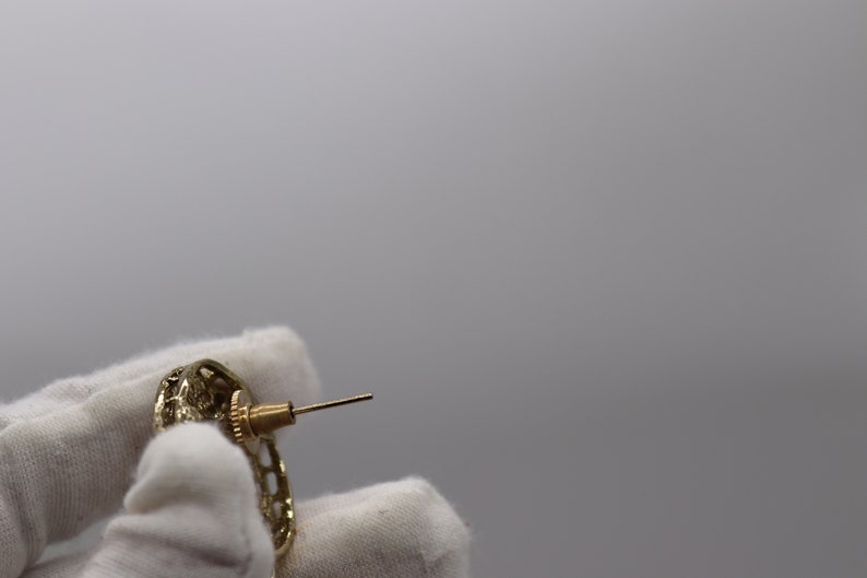 Op de afbeelding: Gouden oorbellen met een gedetailleerd, ingewikkeld ontwerp. De oorbellen hebben een post-sluiting.