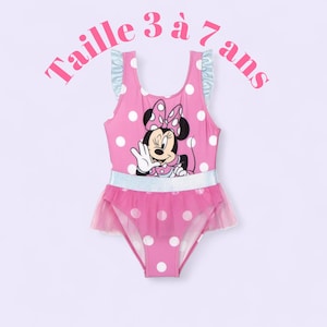Puede incluir: Traje de baño rosa con lunares con Minnie Mouse. El traje de baño de una pieza tiene una falda y tirantes con volantes, con el texto "Taille 3 à 7 ans" en rosa. El traje de baño tiene un cinturón plateado brillante.