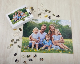 May include: A family of five poses for a photo in a field of green grass and wildflowers. The family is made up of two parents and three children. The parents are standing behind the children, who are sitting on the ground. The family is smiling and looking at the camera. The photo is printed on a 300-piece jigsaw puzzle.