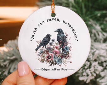 May include: White ceramic Christmas ornament with a black raven and floral design. The ornament features the quote "Quoth the raven, nevermore." and the name "Edgar Allan Poe".