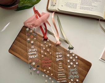 May include: Four clear acrylic bookmarks with floral designs and inspirational quotes. The bookmarks feature the phrases "In Jesus name, Amen!", "The more you pray", "Fruit of the Spirit", and "Give me Jesus".