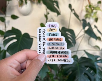 May include: A sticker with a white background and colorful text. The text reads "Fruit of the Spirit" with the scripture reference "Galatians 5:22-23" and lists the nine fruits of the spirit: love, joy, peace, patience, kindness, goodness, faithfulness, gentleness, and self-control.