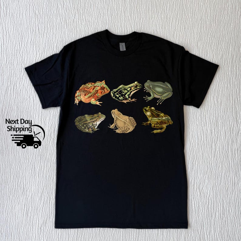 Puede incluir: Camiseta negra con un estampado gr&aacute;fico de seis ranas diferentes en varios colores y poses.