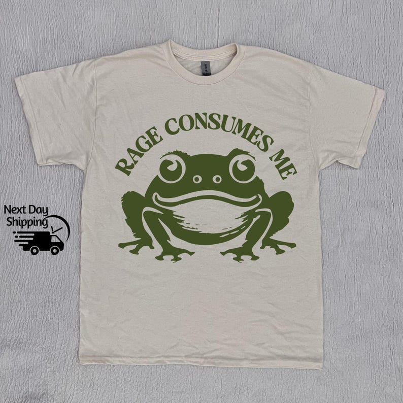 May include: A beige t-shirt with a green frog graphic and the text "Rage Consumes Me".