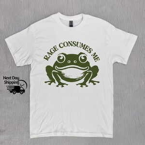 May include: White t-shirt with a green frog graphic and the text "Rage Consumes Me".