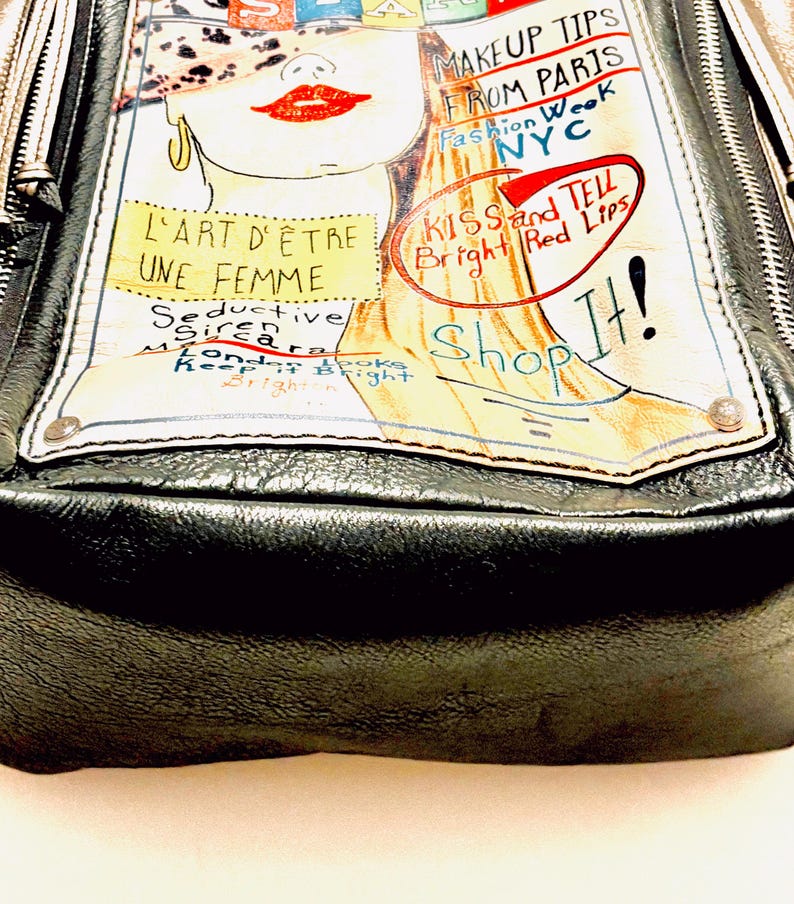 Pode incluir: Bolsa de m&atilde;o de couro preta com uma ilustra&ccedil;&atilde;o colorida. A ilustra&ccedil;&atilde;o apresenta o rosto de uma mulher com l&aacute;bios vermelhos e o texto "MAKEUP TIPS FROM PARIS" e "KISS and TELL Bright Red Lips". A bolsa tem fecho de z&iacute;per.
