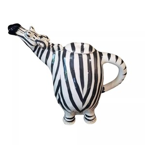May include: A ceramic teapot shaped like a zebra with black and white stripes. The teapot has a spout and handle and stands on two legs.