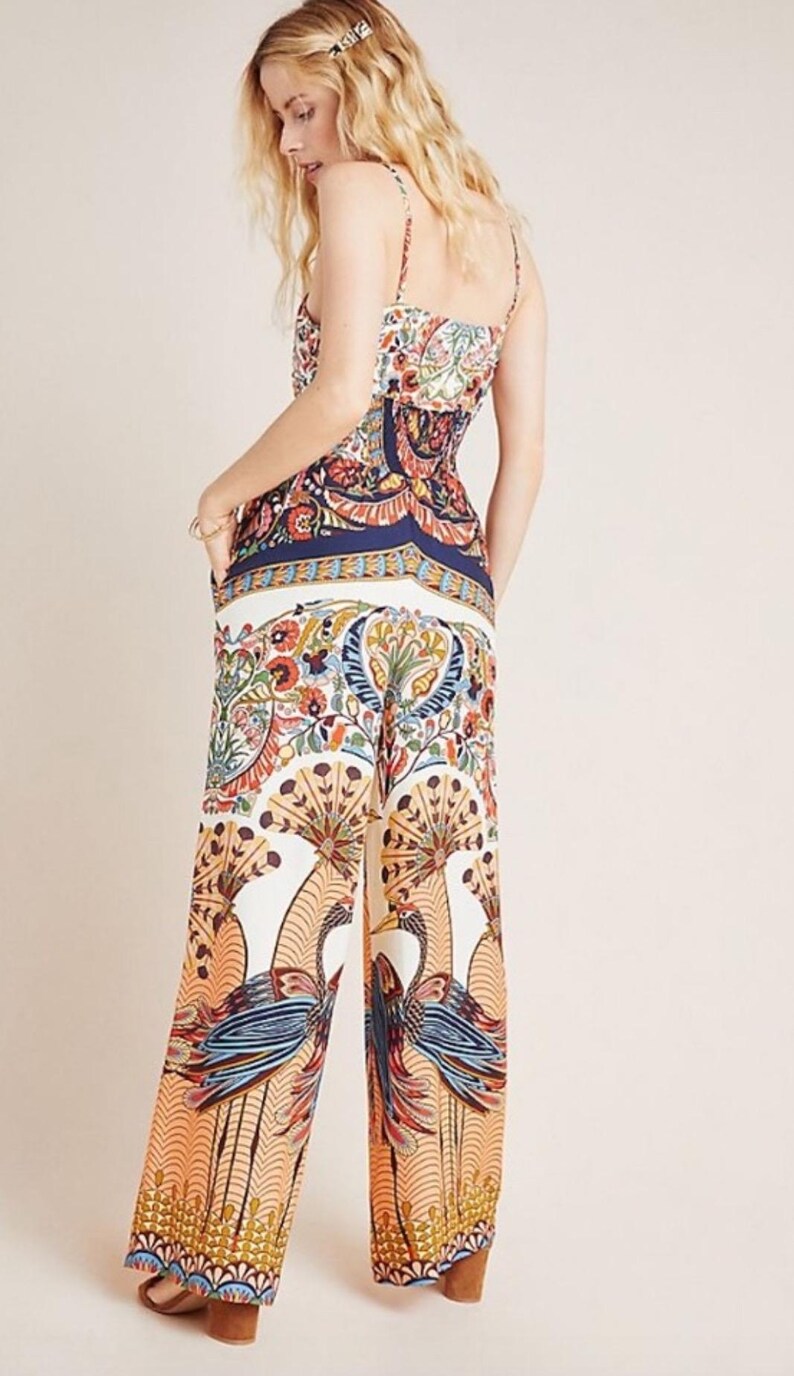 May include: A white jumpsuit with a colorful floral and bird print. The jumpsuit has a fitted bodice and wide-leg pants.