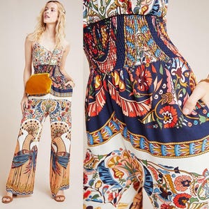 May include: A white and blue patterned jumpsuit with a floral design. The jumpsuit has a smocked waist and wide legs.