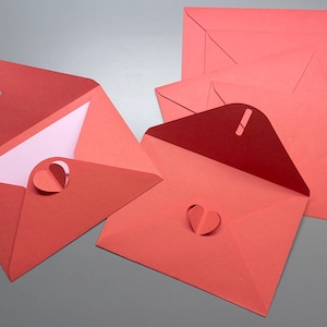 May include: Five red envelopes with a heart-shaped cut-out on the front. The envelopes are open and the inside is visible. The envelopes are made of a textured paper.