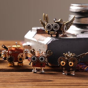 Puede incluir: Cuatro figuras de robots de estilo steampunk con engranajes, alas y detalles de llaves. Los robots son en tonos marrón, dorado y plateado, con intrincados diseños mecánicos. Están dispuestos sobre una superficie de madera.