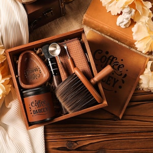 May include: A wooden box set containing coffee-related items. The set includes a small wooden bowl, a jar with the text "Coffee DARCEY", a brush, a scoop, and a small wooden brush. The box is open, revealing the contents.