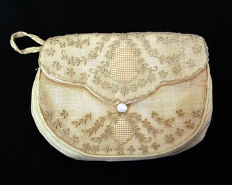 May include: A small, cream-colored, embroidered satin purse with a pearl button closure.