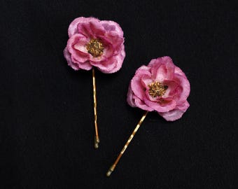Dulces flores de color rosa oscuro en horquillas de bronce.