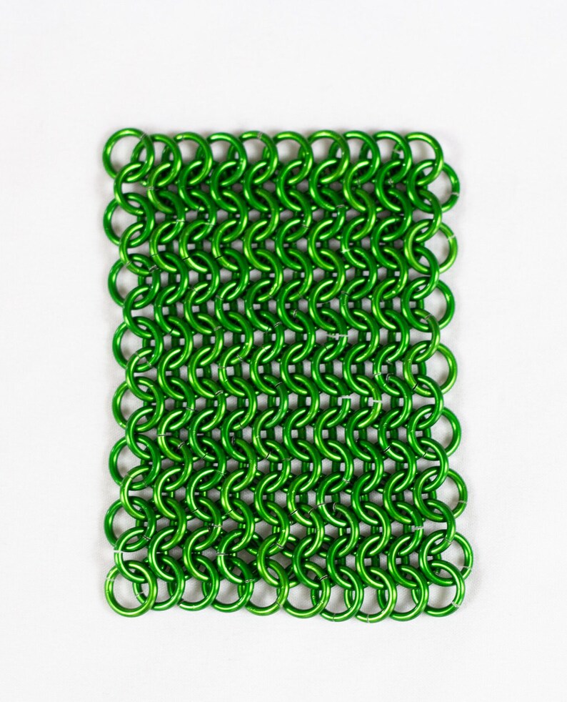 Puede incluir: Una malla de cota de malla de metal verde, hecha de peque&ntilde;os anillos entrelazados.