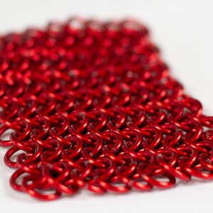 Puede incluir: Un primer plano de una malla de cota de malla roja. La cota de malla est&aacute; hecha de peque&ntilde;os anillos de metal interconectados.