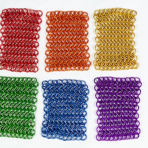 Puede incluir: Seis piezas cuadradas de cota de malla en diferentes colores: rojo, naranja, dorado, verde, azul y morado.