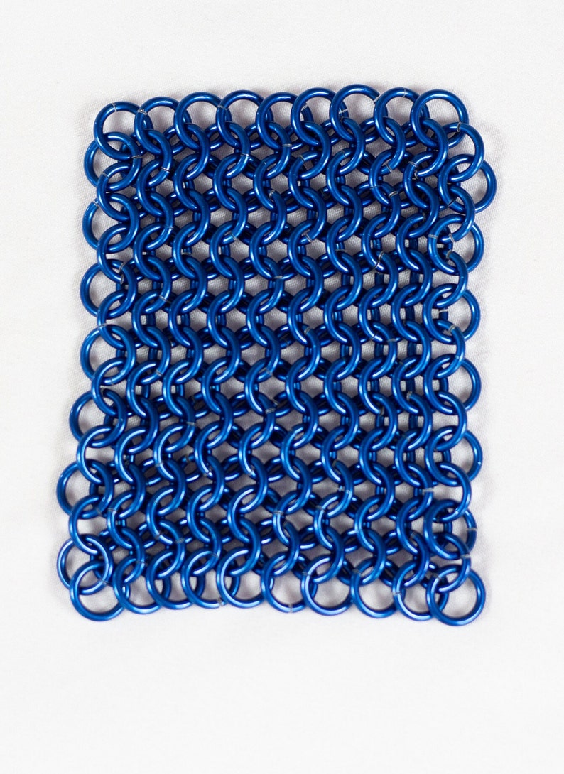 Puede incluir: Una malla de cota de malla de metal azul, hecha de anillos entrelazados.