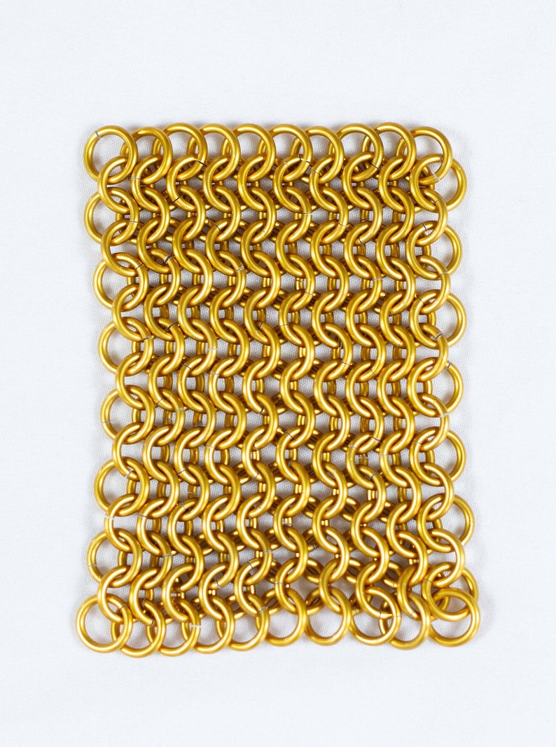 Puede incluir: Un cuadrado de cota de malla dorada, hecho de anillos de metal entrelazados. La cota de malla es un tipo de malla met&aacute;lica tejida.