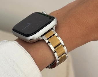 Puede incluir: Una banda de reloj Apple plateada y dorada con una esfera negra.