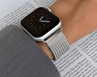 May include: A silver Apple Watch with a black face and a silver Milanese loop band. The watch is on a person's wrist.
