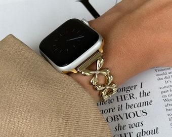 Puede incluir: Una pulsera de reloj dorada con un diseño de flores. La pulsera está unida a un Apple Watch plateado.