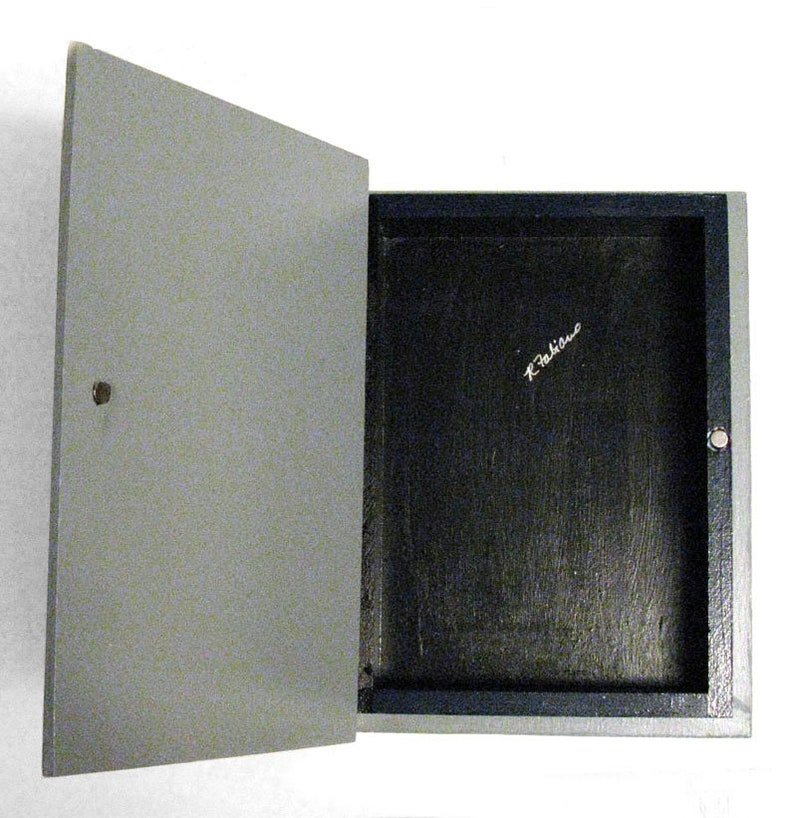 K&ouml;nnte beinhalten: Eine graue Holzkiste mit schwarzem Innenraum. Die Kiste ist ge&ouml;ffnet und der Innenraum ist leer. Die Kiste ist mit "K.Takine" in schwarzer Tinte signiert.