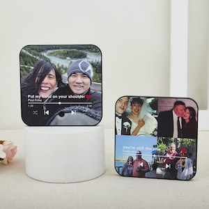 May include: Two black square photo blocks with rounded corners. One displays a photo with the text "Put my hand on your shoulder" and a music player interface. The other shows multiple photos with the text "you're still the one".