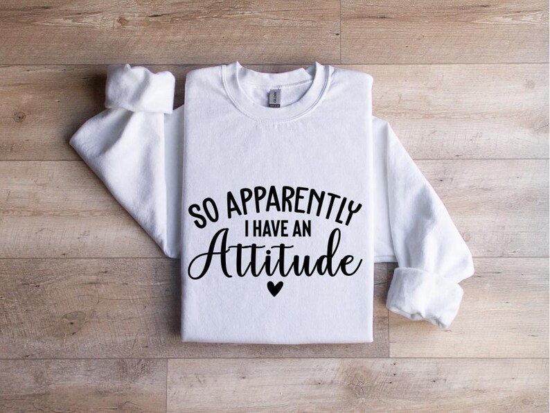 K&ouml;nnte beinhalten: Wei&szlig;es Langarmshirt mit schwarzem Text, der "So Apparently I Have An Attitude" mit einem kleinen Herzsymbol lautet.