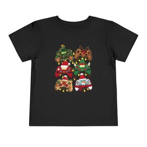 Könnte beinhalten: Schwarzes Kleinkind-T-Shirt mit einer Grafik von sechs weihnachtlichen Videospiel-Controllern. Die Controller sind als Weihnachtsbaum, Rentier, Weihnachtsmann, Lebkuchenmann und Schneemann dekoriert.