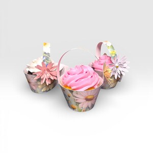 May include: Three cupcakes in decorative paper baskets. The baskets are adorned with a floral daisy pattern and feature pink frosting. Each cupcake is decorated with a paper flower and a handle, creating a charming presentation.