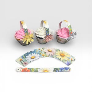 May include: Three cupcakes in decorative paper baskets with floral handles and flower accents. The cupcakes have pink and white frosting. Additional floral cupcake wrappers are also shown.