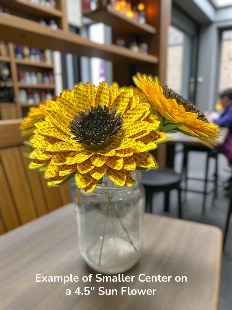 May include: A clear glass jar holds paper sunflowers with yellow petals and dark brown centers. The petals are printed with text. The text on the image reads: "Example of Smaller Center on a 4.5" Sun Flower."